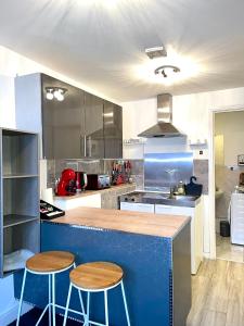 a kitchen with a blue counter and two stools at Charming 1-Bed loft Apartment in Romford in Romford