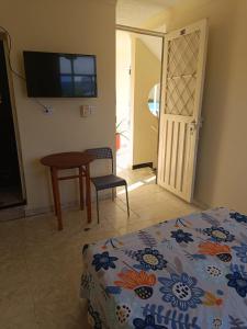 1 dormitorio con cama, mesa y TV en Cambulos House, en Melgar