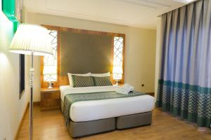 a bedroom with a bed and a lamp and a window at UNITED HOTEL INTERNATIONAL in Yaoundé