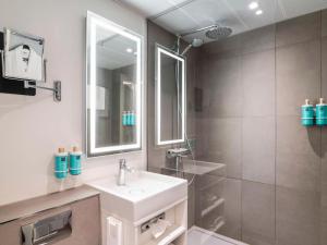 a white bathroom with a sink and a shower at Novotel Amsterdam City in Amsterdam