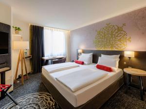 a hotel room with a large bed with red pillows at Mercure München City Center in Munich