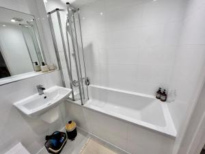 a white bathroom with a sink and a shower at 2-bed flat in central Borehamwood location in Borehamwood