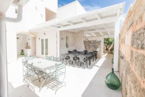 an outdoor patio with white tables and chairs at Capperi !! Holiday Rentals in Morciano di Leuca