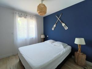 1 dormitorio con 1 cama grande y pared azul en La Villa des Verdiers standing 6 personnes, en Andernos-les-Bains