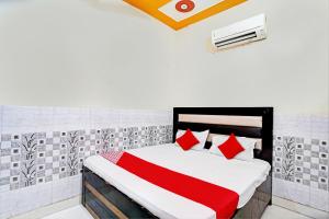1 dormitorio con 1 cama con almohadas rojas y blancas en OYO Flagship S.K .hotel en Panchli