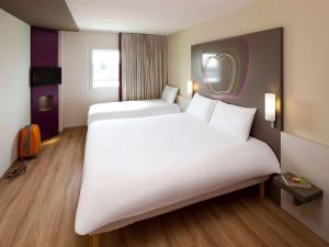 a hotel room with two beds and a mirror at Hotel Ibis Styles Lleida Torrefarrera in Lleida