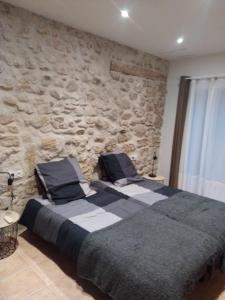 2 camas en un dormitorio con pared de piedra en Mas de la Sauline, en La Roque-d'Anthéron