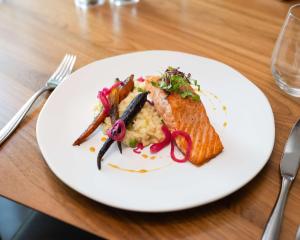 a white plate with fish and vegetables on a table at Conrad New York Downtown in New York
