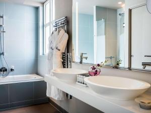 a bathroom with two white sinks and a tub at Cures Marines Hotel & Spa Trouville - MGallery Collection in Trouville-sur-Mer