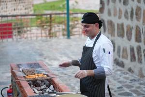 un hombre está cocinando comida en una parrilla en Dibba Mountain Park Resort, en Fujairah