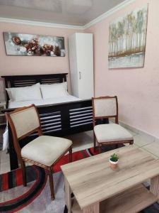 um quarto com uma cama, 2 cadeiras e uma mesa em Private outside room with own bathroom em Joanesburgo