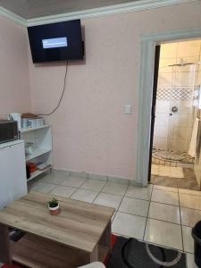 uma sala de estar com uma mesa e uma televisão na parede em Private outside room with own bathroom em Joanesburgo