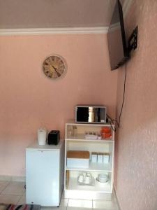 a small white refrigerator and a clock on a wall at Private outside room with own bathroom in Johannesburg