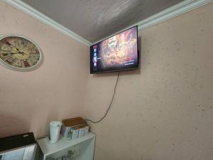 a television hanging on a wall with a clock at Private outside room with own bathroom in Johannesburg