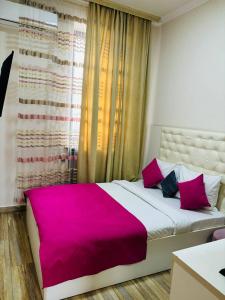 um quarto com uma cama grande e um cobertor rosa em Alex Hotel em Yerevan