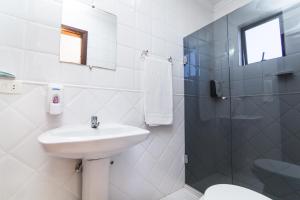 a white bathroom with a sink and a shower at Hotel Caieiras in Guaratuba
