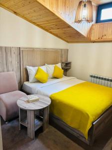 Un dormitorio con una cama con sábanas amarillas y una mesa. en Alex Hotel, en Ereván