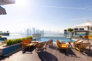 a rooftop patio with tables and chairs and a view of the city at Cosy Studio at Palm Jumeirah in Dubai