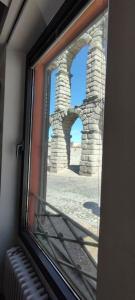 a window with a view of a stone building at Casa bajo el acueducto con plaza de garaje in Segovia