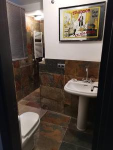 a bathroom with a white toilet and a sink at Casa bajo el acueducto con plaza de garaje in Segovia