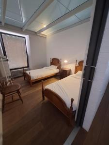 a room with two beds and a chair and a window at Casa bajo el acueducto con plaza de garaje in Segovia