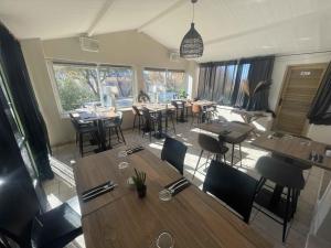 a restaurant with wooden tables and chairs and windows at Les Loges du Luberon in Coustellet