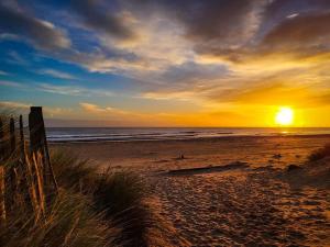 a sunset on a beach with the ocean at Chalet 192, Hemsby - Two bed chalet, sleeps 5, pet friendly, bed linen and towels included in Hemsby