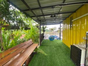 - un patio avec un banc en bois et un bâtiment jaune dans l'établissement บ้านอัญชัน, 
