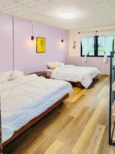 two beds in a room with pink walls and wooden floors at บ้านอัญชัน 
