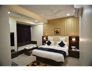 um quarto com uma cama grande e uma televisão em Hotel Royal Residency, Vadodara em Vadodara