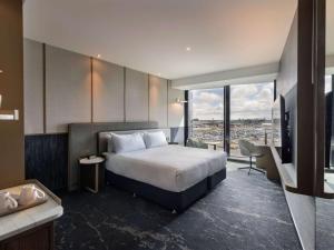 a hotel room with a bed and a television at Pullman Auckland Airport in Auckland