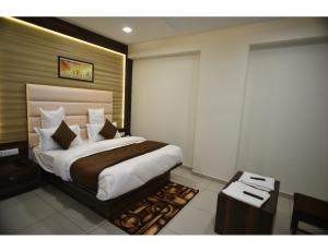 um quarto com uma cama grande e uma mesa em Hotel Royal Residency, Vadodara em Vadodara
