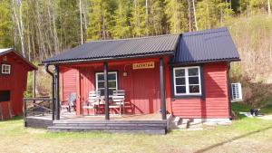 une cabine rouge avec une terrasse en gazon dans l'établissement Vikinggård Cottages, à Höljes 145 autres photos