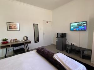 um quarto com uma cama e uma televisão na parede em No 1 Guest house em Cidade do Cabo