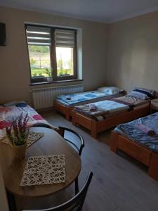 Zimmer mit 4 Betten, Tisch und Stühlen in der Unterkunft Lawendowy zakątek in Graboszyce