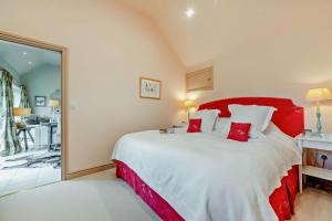 a bedroom with a large bed with red accents at Guddlebrook Two in Great Rollright