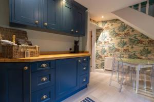 kuchnia z niebieskimi szafkami i stołem z krzesłami w obiekcie Charming Coates Cottage w mieście Baslow