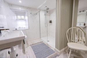 a bathroom with a shower and a sink and a chair at Charming Coates Cottage in Baslow