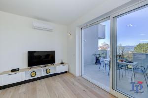 uma sala de estar com uma televisão e uma porta de vidro deslizante em DesenzanoLoft Smeraldo Family apartment em Desenzano del Garda