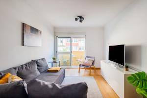 a living room with a gray couch and a tv at Olaias Flat (with Free Parking) in Lisbon