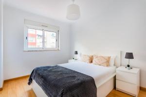 a white bedroom with a bed and a window at Olaias Flat (with Free Parking) in Lisbon