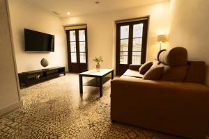 Una sala de estar con un sofá y un televisor. en Apartamentos Consistorio Live, en Jerez de la Frontera