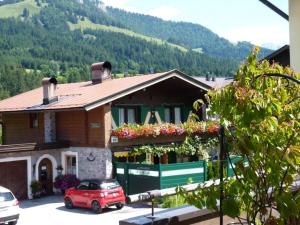 a house with a red car parked in front of it at Guest house pension Neumayer in Fieberbrunn