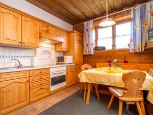 a kitchen with wooden cabinets and a table with chairs at Guest house pension Neumayer in Fieberbrunn