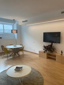 ein Wohnzimmer mit einem Tisch und einem TV an der Wand in der Unterkunft Soho Moraleja II duplex in Alcobendas