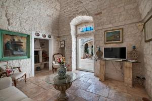een woonkamer met een tv en een stenen muur bij Casale San Giusi by Perle di Puglia in San Michele Salentino