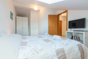 a bedroom with a white bed with a tv on it at Apartments Mimoza in Baška