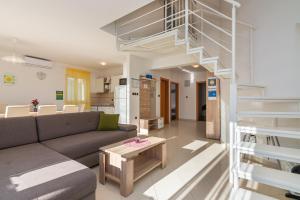 a living room with a couch and a spiral staircase at Apartments Mimoza in Baška