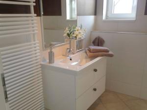 a white bathroom with a sink and a mirror at Holiday apartment Schliekieker in Kopperby +2 photos