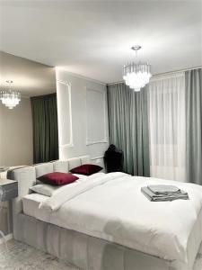 a large white bed in a bedroom with chandeliers at STUDIO 92- URBAN PLAZA in Braşov